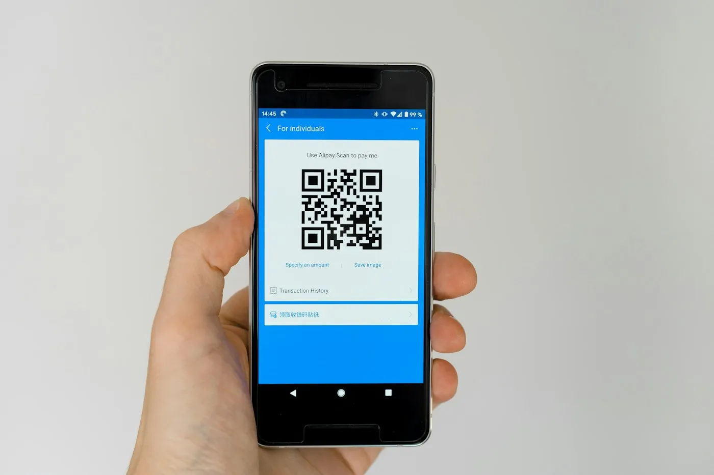 A hand holding up a phone that shows a QR code